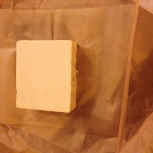 May include: A rectangular bar of soap wrapped in brown paper.