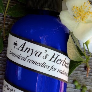 May include: A blue bottle with a white label that reads "Anya's Herbal botanical remedies for radiant skin".