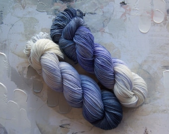 May include: Two skeins of yarn, one white and one blue, with a gradient of color from dark to light.