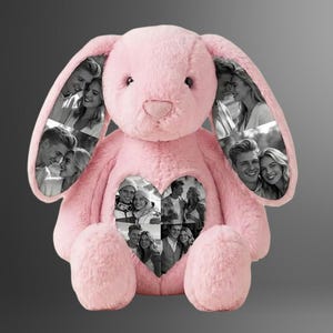 Op de afbeelding: Een roze pluche konijn met zwart-wit foto's van koppels in de oren en een hartvormige uitsparing op de borst. Een gepersonaliseerd cadeau.