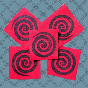 Può includere: Cinque toppe in tessuto di forma quadrata di colore rosso vivace, ciascuna caratterizzata da un audace motivo a spirale nero antracite stampato al centro. Le toppe sono disposte a grappolo, mostrando un motivo grafico coerente su tutti i pezzi.