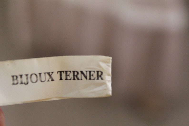 May include: A white tag with the text "Bijoux Turner" printed in black.