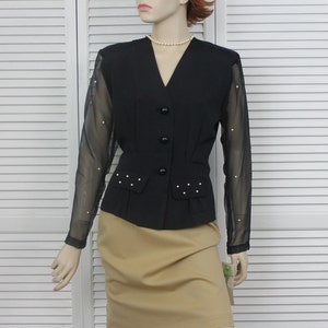 May include: A black blazer with sheer sleeves featuring pearl embellishments. The blazer has a v-neckline and a button closure.