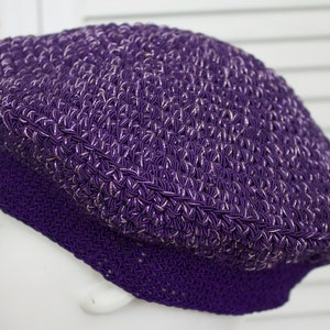 May include: A purple crocheted beret with a textured design. The beret has a subtle sheen and is made of a soft, pliable material.