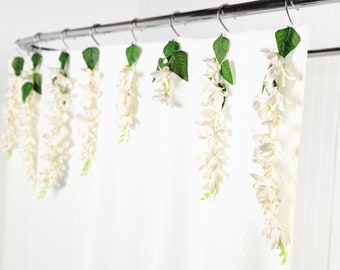 May include: White shower curtain with white flower garlands hanging from the shower rod.