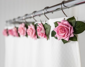 May include: A white shower curtain with pink fabric roses attached to the curtain rings.