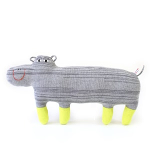 May include: A gray and white striped knitted hippopotamus plush toy with yellow feet. The toy has a smiling face with red stitching.