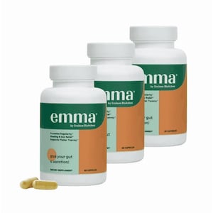 May include: Three white supplement bottles with green and orange labels. The labels read "emma" and "give your gut a vacation!". Two capsules are in front of the bottles. The bottles are dietary supplements.