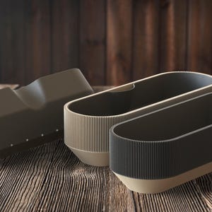 May include: Three modern, oval-shaped planters in shades of brown and beige sit on a wooden surface. The planters have a ribbed texture on the upper portion and a smooth, solid base. The background is a dark wooden wall.