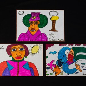 May include: Three rectangular drawings on white paper featuring colorful marker illustrations. One depicts a person in a purple outfit and hat, another shows a person with a yellow sun, and the third shows a blue figure with a bird and tree.