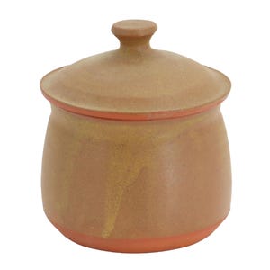 Puede incluir: Un tarro de cerámica de color tostado con una tapa a juego que presenta un pequeño pomo. El tarro tiene un acabado mate suave con sutiles variaciones de tono y un borde base visible de color terracota, formando un recipiente funcional.