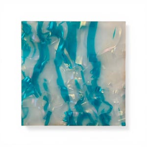 Pode incluir: Placa quadrada de acrílico iridescente com um padrão marmorizado. O design apresenta faixas de azul turquesa sobre um fundo branco. O material tem um acabamento brilhante e uma aparência texturizada, sugerindo um elemento decorativo ou artesanal.