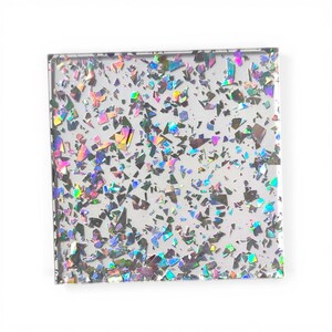 Peut inclure: Sous-verre carré en verre transparent avec des morceaux irisés en forme de confettis incrustés. Les confettis reflètent plusieurs couleurs, dont le rose, le vert et le bleu. Le sous-verre mesure environ 10 cm x 10 cm.
