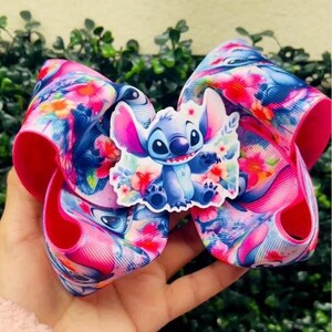 May include: A large, colorful bow with a floral pattern in pink, blue, and white, featuring a Stitch character embellishment. The bow is held in a hand and the text "Ideas for your next diy project... Bow centers" is visible.