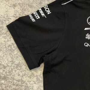May include: Black short-sleeved t-shirt with white logos on the sleeve and chest. The logos include the words "SON", "SE", "ELLI", and "HURI". The shirt has a crew neck and a white stripe along the shoulder.