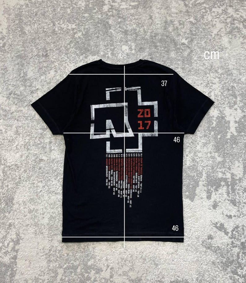 K&ouml;nnte beinhalten: Ein schwarzes Kurzarm-T-Shirt mit einer wei&szlig;en und roten Grafik auf der R&uuml;ckseite. Das Design zeigt ein stilisiertes Kreuz-Logo, den Text 2017 und eine Liste von Tourdaten. Wei&szlig;e Messlinien und Zahlen in cm sind &uuml;ber das Kleidungsst&uuml;ck gelegt.