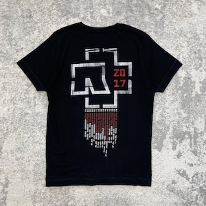 K&ouml;nnte beinhalten: Ein schwarzes Kurzarm-T-Shirt mit einer gro&szlig;en wei&szlig;en und roten Grafik auf der R&uuml;ckseite. Das Design enth&auml;lt ein stilisiertes Logo, den Text 20 17 und eine Liste von Tourdaten und Orten, die in wei&szlig;er und roter Schrift unter der Grafik stehen.
