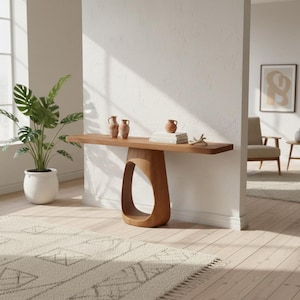 Puede incluir: Una consola de madera con una base ovalada abierta única. La encimera muestra tres pequeños jarrones de terracota, una pila de libros y una estrella de mar decorativa. Una planta en maceta y una alfombra estampada también son visibles en la habitación.