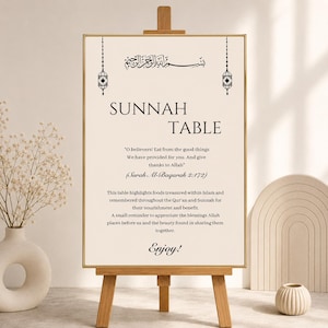 May include: A wooden easel displays a beige sign with black text and decorative elements. The sign reads "SUNNAH TABLE" and includes a quote from the Quran. The sign is decorated with hanging lanterns and calligraphy. A vase with flowers is on the left.