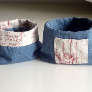 Peut inclure: Deux paniers de rangement en tissu bleu avec une doublure en tissu blanc. Un panier a un patch en tissu blanc avec un motif d'ange rouge. L'autre panier a une doublure en tissu blanc avec une &eacute;criture rouge.