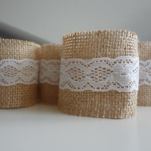 Peut inclure: Quatre manchons cylindriques en toile de jute avec une bande de dentelle blanche. La toile de jute est de couleur beige naturel et la dentelle est blanche. Idéal pour la décoration rustique ou les travaux manuels.