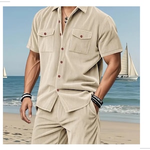 May include: Beige corduroy shirt and shorts set. The short-sleeved shirt has two chest pockets and brown buttons. The shorts have pockets. The background shows a beach scene with sailboats.