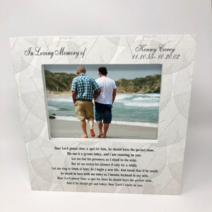 May include: A white wooden picture frame with a leaf pattern border. The frame holds a photo of two people walking on a beach. The frame has the text "In Loving Memory of Kenny Carey 11.10.55-10.20.02" and a poem about remembering a loved one.