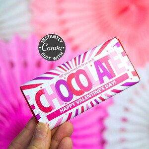 May include: A Valentine's Day-themed chocolate bar wrapper with the word "CHOCOLATE" in pink and purple. The wrapper also includes the text "All you need is love and HAPPY VALENTINE'S DAY!" on a white background with pink and purple stripes.