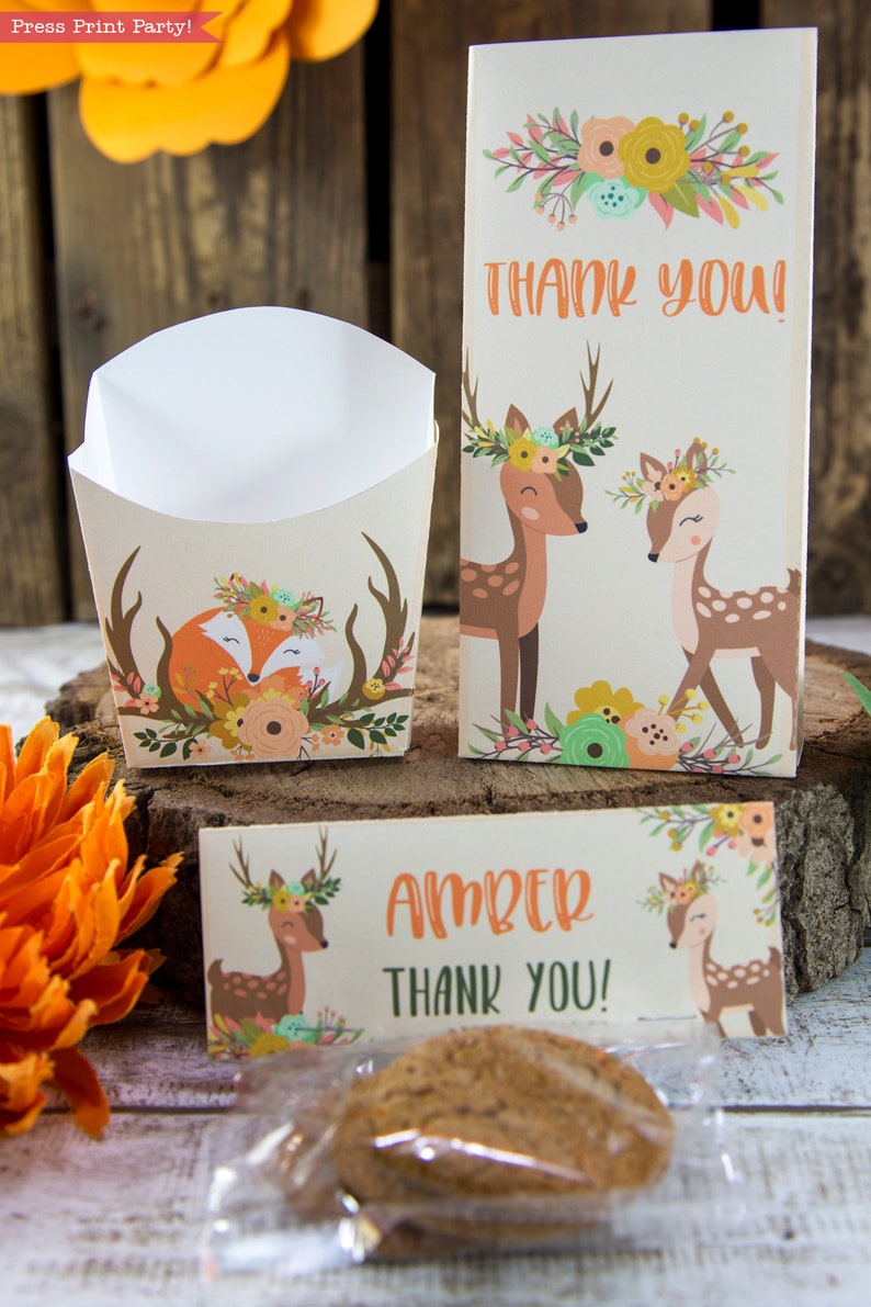 May include: A set of party favor boxes with a woodland theme. The boxes feature a fox and deer with floral crowns. The boxes are decorated with a brown, orange, and green color scheme. The boxes are labeled with the text "Thank You!" and "Amber Thank You!"