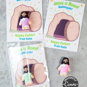 Pode incluir: Cart&otilde;es de P&aacute;scoa com o texto "Jesus ressuscitou! Aleluia!" e "Feliz P&aacute;scoa! De Katie." Os cart&otilde;es apresentam uma ilustra&ccedil;&atilde;o de Jesus saindo de um t&uacute;mulo. Um cart&atilde;o &eacute; embalado com uma pequena figura de Jesus.