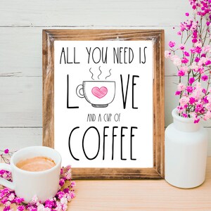 K&ouml;nnte beinhalten: Druckbarer Kaffeebar-Schild mit braunem Holzrahmen. Das Schild sagt "Alles was du brauchst ist Liebe und eine Tasse Kaffee" mit einer stilisierten Kaffeetasse und einem Herzen. Das Schild befindet sich auf einer Holzoberfl&auml;che mit einer Tasse Kaffee und rosa Blumen.