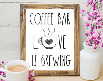 Könnte beinhalten: Druckbarer Schild in einem braunen Rahmen mit dem Text "Coffee Bar Love is Brewing" und einer Comic-Kaffeetasse mit einem Herzen. Das Schild befindet sich auf einem Holzgrund mit rosa Blumen.