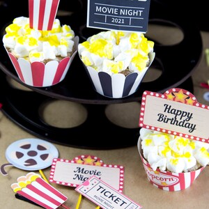 Op de afbeelding: Cupcake-toppers met een filmthema met rood-wit gestreepte popcorn-emmers, een bioscoopkaartje, een filmrol en een klapbord met de tekst "FILMAVOND 2021".