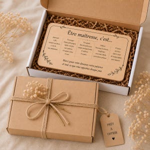 May include: A gift set featuring a wooden plaque with French text, presented in a cardboard box. The plaque reads "&Ecirc;tre ma&icirc;tresse, c'est..." and is decorated with floral accents. The box is tied with twine and a small tag.