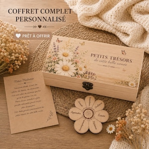 Può includere: Una scatola regalo in legno con un design floreale, con margherite e farfalle, e la scritta "PETITS TRÉSORS". Sono presenti anche un sottobicchiere in legno a forma di fiore e una nota scritta a mano.