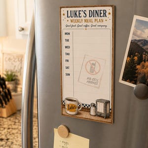 May include: A rectangular magnetic weekly meal planner board titled Luke's Diner. It features the text Good food. Good coffee. Good company., a list of days from Mon to Sun, and a graphic of a no cell phones sign, a coffee mug, and a napkin holder.
