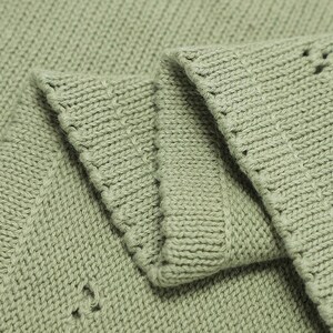 May include: A sage green knitted fabric featuring a dense, uniform stockinette stitch pattern. The material is folded to reveal multiple layers, showcasing the consistent texture, the soft matte finish of the yarn, and the clean, ribbed edges.