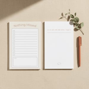 May include: Two notepads with text and a pen on a neutral surface. One notepad says "Nothing Missed" with a checklist. The other notepad says "Let me write that down before I forget it". A pen is placed next to the notepad.