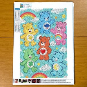 May include: A diamond painting kit featuring six colorful cartoon bears with various symbols on their bellies, set against a light blue sky with white cloud and rainbow accents. The image is labeled "Size: 20*30".