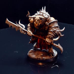 May include: A detailed miniature figure of a minotaur warrior, painted in shades of brown, tan, and red. The minotaur is depicted with horns, armor, and a spiked weapon. The figure is standing on a circular base.