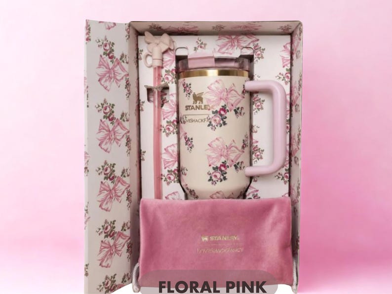 May include: A cream-colored Stanley tumbler with a pink floral and bow pattern, featuring a matching pink straw with a bow topper and a pink velvet pouch, all housed in a decorative box with the same floral print and the text FLORAL PINK.