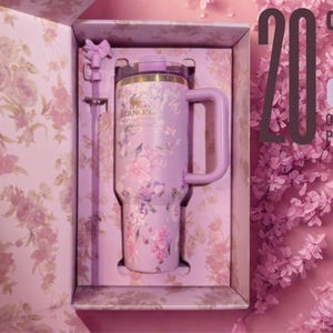 May include: A light purple Stanley tumbler with a floral pattern, a matching handle, and a straw, presented in a decorative box with a floral interior. The text 20% OFF ON ALL PRODUCTS is visible on the right side of the image.