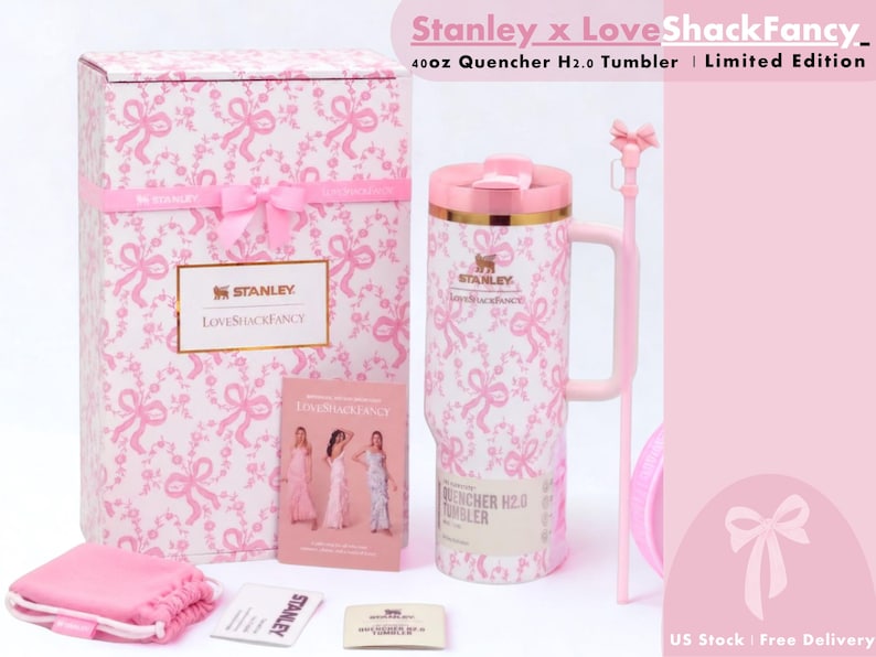K&ouml;nnte beinhalten: Ein 1,18-Liter Stanley x LoveShackFancy Quencher H2.0 Becher mit einem rosa-wei&szlig;en Schleifenmuster, einem passenden rosa Strohhalm mit Schleifenaufsatz, einer Geschenkbox mit rosa Schleife, einem kleinen rosa Beutel und Infokarten mit Markentext.