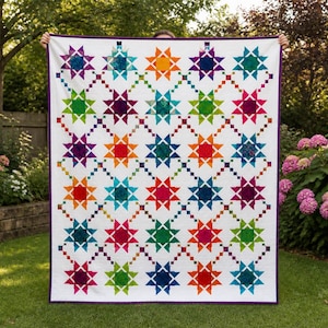 May include: A colorful quilt with a white background and a repeating pattern of star shapes in various colors, including red, orange, yellow, green, blue, and purple. The stars are connected by a dotted line pattern. The quilt has a purple border.