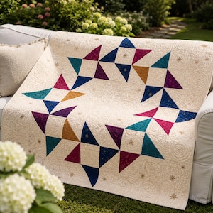 May include: A cream-colored quilt featuring a central ring of geometric star patterns in shades of teal, magenta, navy blue, and gold. The fabric has an intricate quilted texture with small embroidered star accents throughout the cream background.