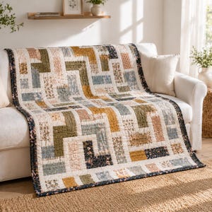 May include: A patchwork quilt with a geometric design, featuring rectangular blocks in various colors and patterns. The quilt includes shades of beige, green, gold, and blue, with floral and checkered accents. A dark blue border with pink floral details frames the quilt.