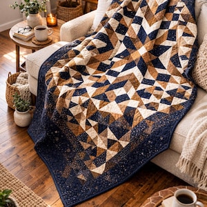 Op de afbeelding: Een geometrisch patroon quilt in marineblauw, bruin en crème, gedrapeerd over een crèmekleurige bank. De quilt heeft een herhalend ontwerp van driehoeken en ruiten. De kamer is ingericht met planten, een lamp en koffiekopjes. Afmetingen: ongeveer 200 cm x 200 cm.