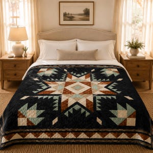 May include: A black quilt with a geometric starburst design in shades of brown, teal, and cream. The quilt is on a bed with white linens and wooden nightstands. The overall theme is Southwestern decor.