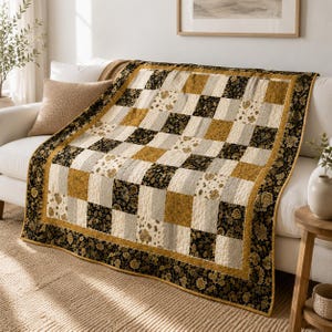 May include: A patchwork quilt featuring a repeating checkerboard pattern of black, mustard yellow, and cream squares. The black squares display a floral print, while the mustard and cream squares have a textured, solid-colored appearance.