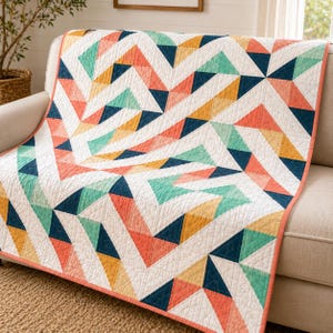 Peut inclure: Un quilt présentant un motif géométrique de triangles dans des tons corail, bleu sarcelle, bleu marine et jaune moutarde sur fond blanc. Le tissu a une texture piquée visible et est bordé d'une bordure corail unie sur les bords.